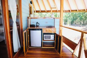 Une petite cuisine équipée comprenant un réfrigérateur, un four à micro-ondes et des étagères en bois.