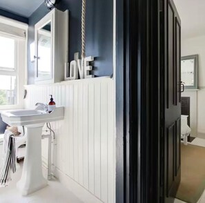 Bathroom features a pedestal sink, large mirror, and a window.