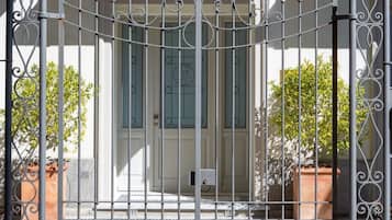 A metal gate with decorative elements, a door with a window, and potted plants.