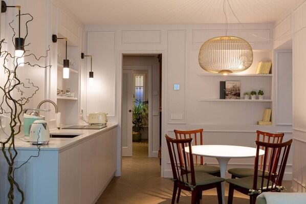 A modern kitchen with a central island, pendant lighting, and a dining area with wooden chairs. - Suite Corti Cernobbio-Central, 1 minute stroll to Lake/Private Parking (Cernobbio)