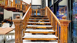 Una scala in legno con gradini in marmo e balaustre elaborate, che conduce a una zona al secondo piano con vista sulla strada.