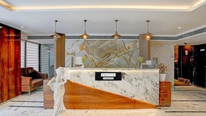 Una reception con piano in marmo, elementi in legno e un cartello con la scritta 'PALETTE & Company Service'.