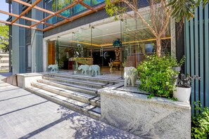 Une entrée d’hôtel moderne avec une façade en verre, des marches en marbre et des sculptures d’animaux décoratives.