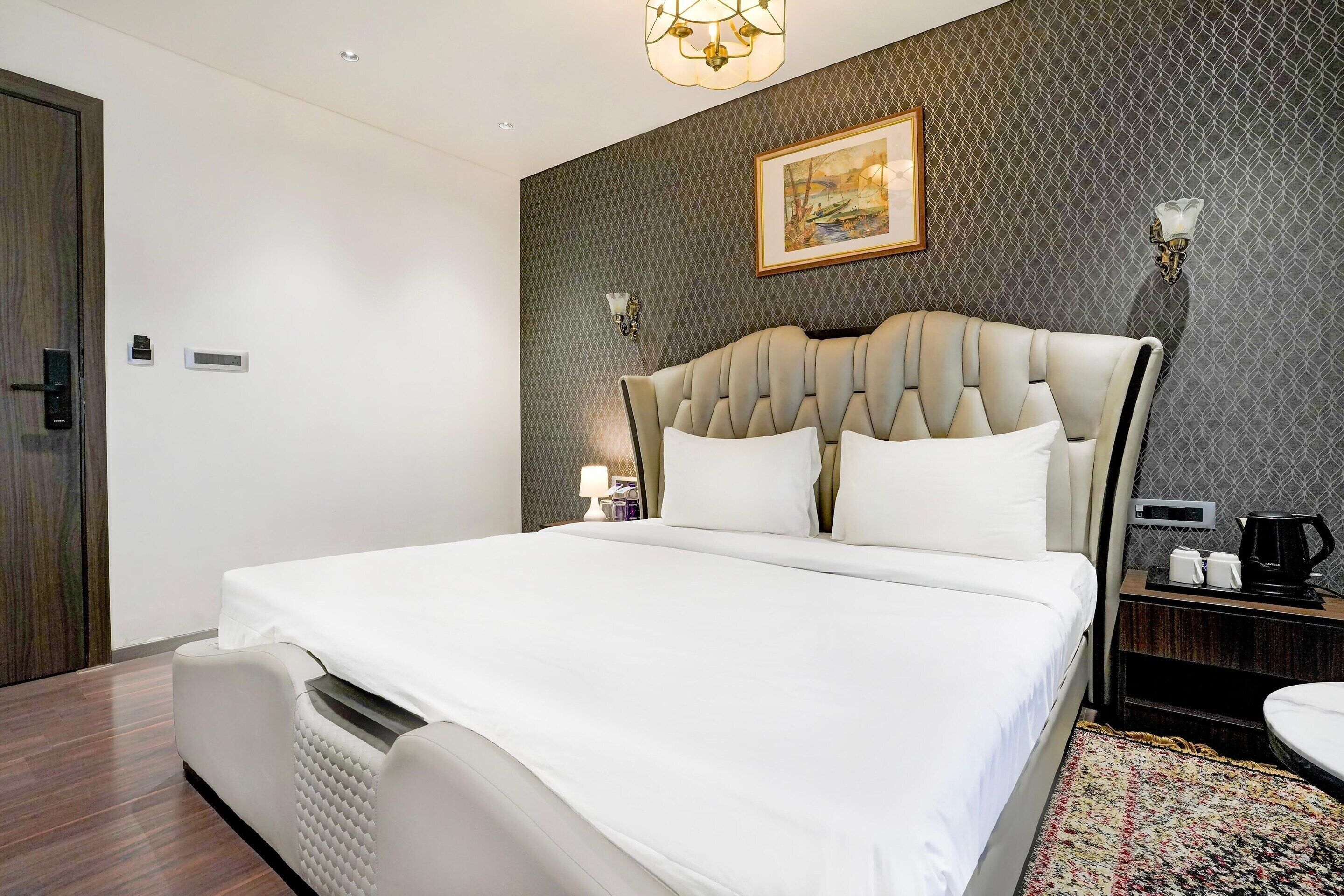 Una camera d'albergo moderna con un letto grande, un comodino con una lampada e un quadro appeso al muro.