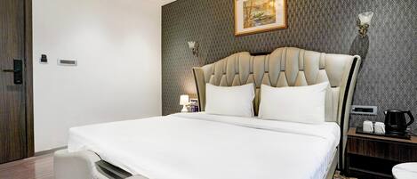 Una camera d'albergo moderna con un letto grande, un comodino con una lampada e un quadro appeso al muro.