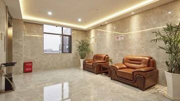 A spacious lobby with a high ceiling, a large window, and a seating area with leather sofas.