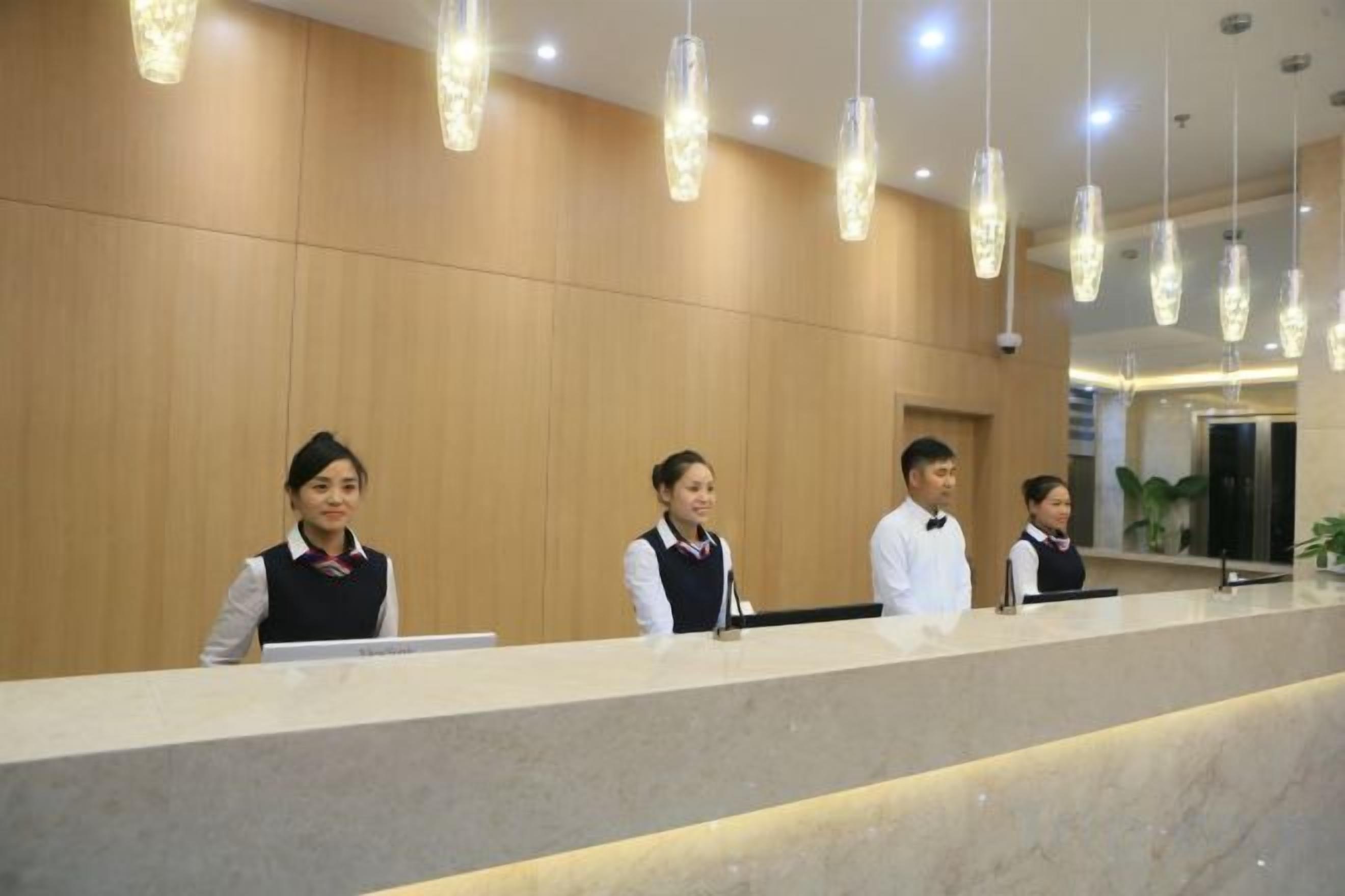 A reception desk with four staff members, a marble counter, and pendant lighting.