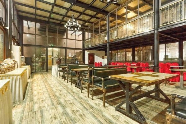 A spacious restaurant with high ceilings, exposed beams, and a mix of seating including tables and booths.