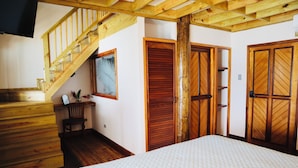 Un dormitorio con una escalera de madera, una cama, una silla y un armario.