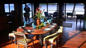 Un espace repas avec une table en bois, des chaises et une vue sur la mer.
