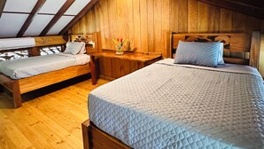 Un dormitorio acogedor en el ático con dos camas, paredes de madera y techo inclinado.