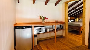 Una cocina compacta con lavavajillas integrado, microondas y encimera de madera. Una pequeña mesa con un jarrón de flores está colocada en el centro.