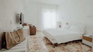Hotellihuone, jossa on sänky, työpöytä, tuoli, televisio ja laukku.
