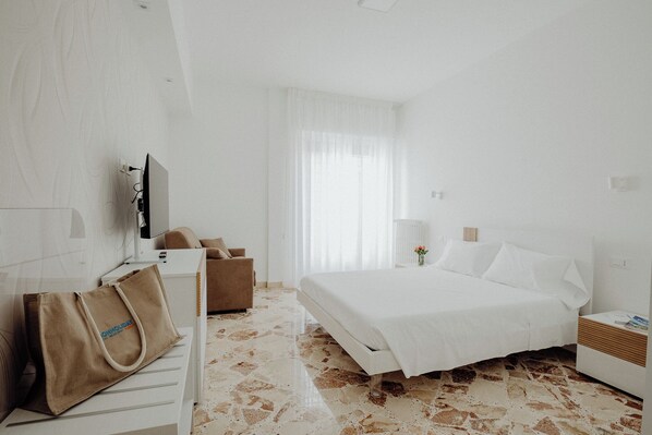 A hotel room with a bed, a desk, a chair, a TV, and a bag.