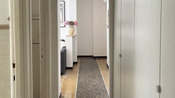 A hallway with white walls, a speckled floor, and a door on the left. - HOUSE OF MIA IN PRATI | VATICAN MUSEUM | OLYMPIC STADIUM (Roma)