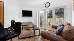 A modern living room with a TV, a wooden table, and a brown sofa.