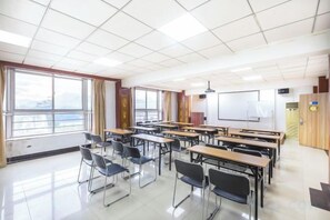 Un aula con escritorios dispuestos en filas, una pizarra y una pantalla para proyector.