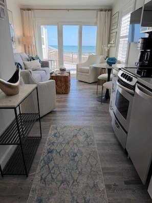 Uma sala de estar moderna com vista para o mar, uma cozinha com fogão e um espaço para refeições.
