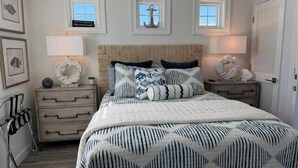 A bedroom with a bed, two nightstands, a dresser, and a window with a view. - Dazzling Oceanfront Condo - Perfect for a Couples Getaway! By Williamson Realty (Ocean Isle Beach)