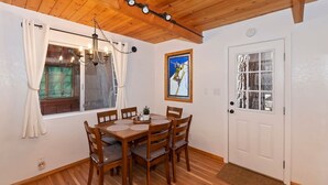 Ein Essbereich mit einem Holztisch und Stühlen, einer Kandelaber und einem fenster mit Vorhängen.