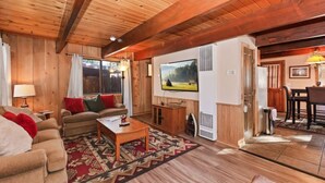 Un salon chaleureux avec des murs et un plafond en bois, un canapé, une table basse et un téléviseur.