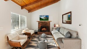 A living room with a fireplace, a sofa, a chair, and a patterned rug. - Peaceful Sunshine Chalet with Hot Tub (Big Bear)