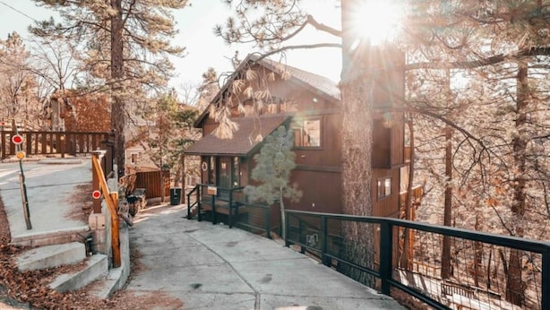 A cabin with a staircase leading to a deck, surrounded by trees. - Moonridge Mountain Retreat (Big Bear)