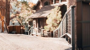 A rustic wooden building with a porch and a fenced area. - Moonridge Mountain Retreat (Big Bear)