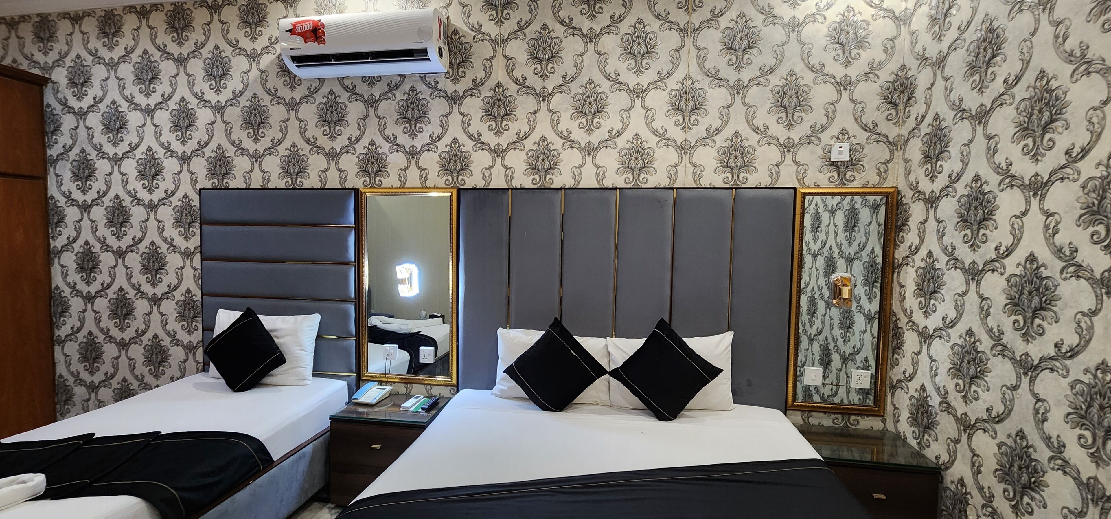 Habitación de hotel con dos camas, un espejo grande y aire acondicionado de pared.