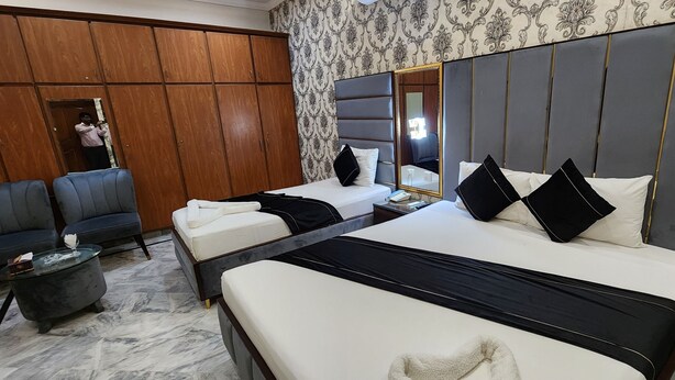 A hotel room with two beds, a sofa, a marble floor, and a large mirror. - Red Fort Hotel Gulberg (Lahore)