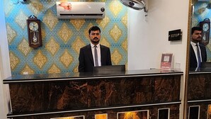 A reception desk with a marble counter, a clock, and a wall-mounted air conditioner. - Red Fort Hotel Gulberg (Lahore)