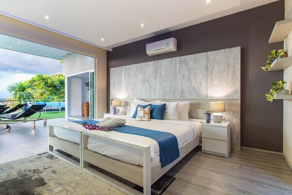 A modern bedroom with a large bed, bedside lamps, and an air conditioning unit.