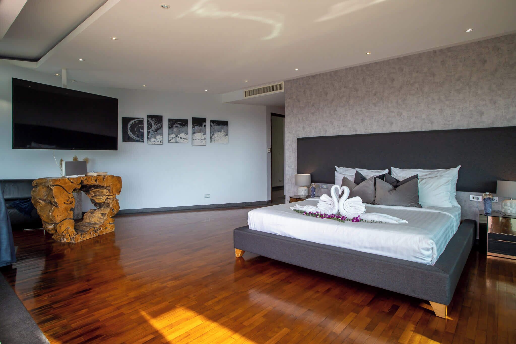 Una habitación de hotel moderna con una cama grande, un televisor de pantalla plana, un detalle decorativo de piedra y obras de arte en las paredes.