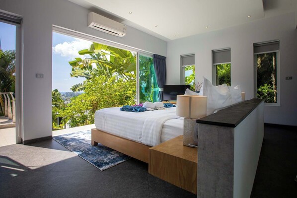 Un dormitorio moderno con una cama grande, un escritorio y vistas a zonas verdes.