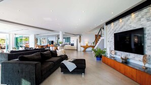 A modern living room with a large flat-screen TV mounted on a stone-textured wall, a dark-colored sofa, and a wooden console table with decorative items.