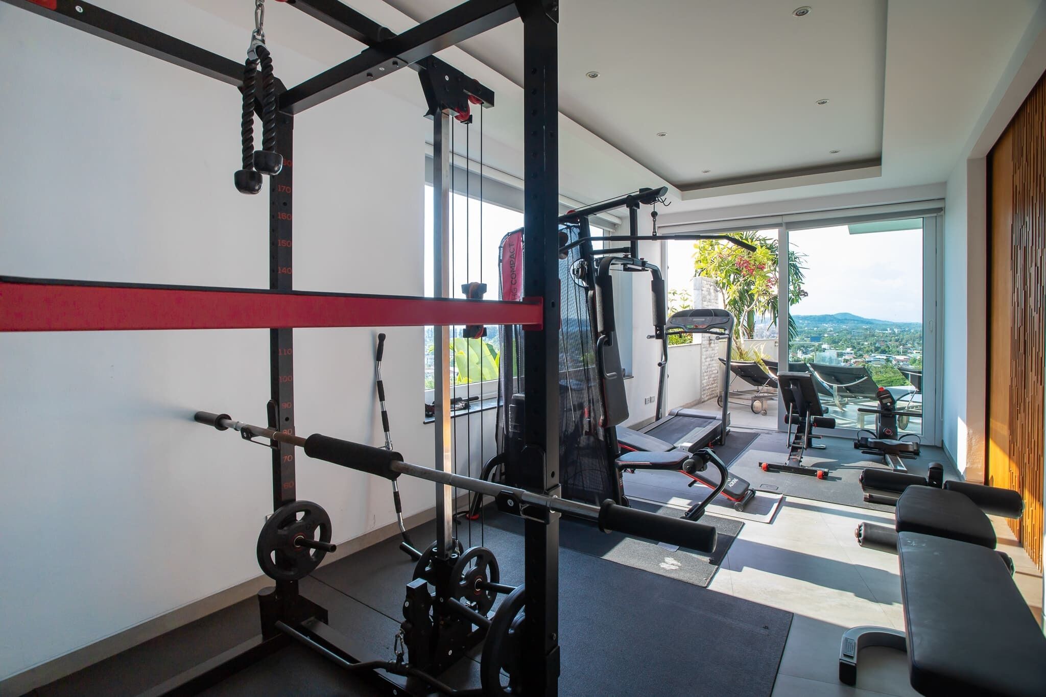 A modern gym with a weightlifting area, cardio machines, and a bench.
