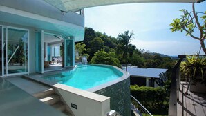 A modern house with a swimming pool, glass doors, and a view of lush greenery.