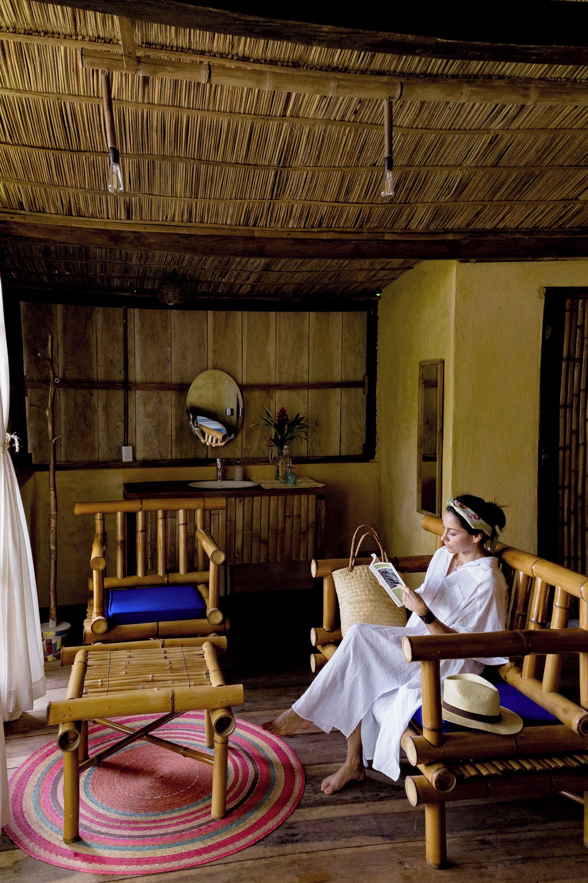 A room with a thatched roof, a wooden bench, a small table, and a mirror on the wall.