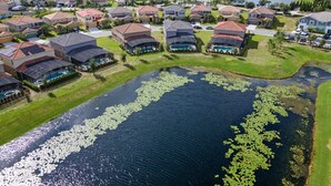 Zona residencial con casas, un lago y un campo de golf al fondo.