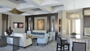 Una sala de estar moderna con un sofá blanco, una mesa de centro y una zona de comedor con barra.
