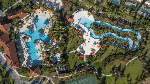 Vista aérea de un complejo turístico con varias piscinas, un tobogán de agua y una cancha de tenis.
