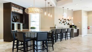Una cocina moderna con una isla central, taburetes de bar, iluminación colgante y un elemento decorativo en la pared.