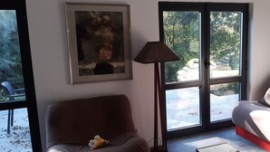 Een woonkamer met een bruine bank, een witte bank, een ingelijst kunstwerk en een vloerlamp.