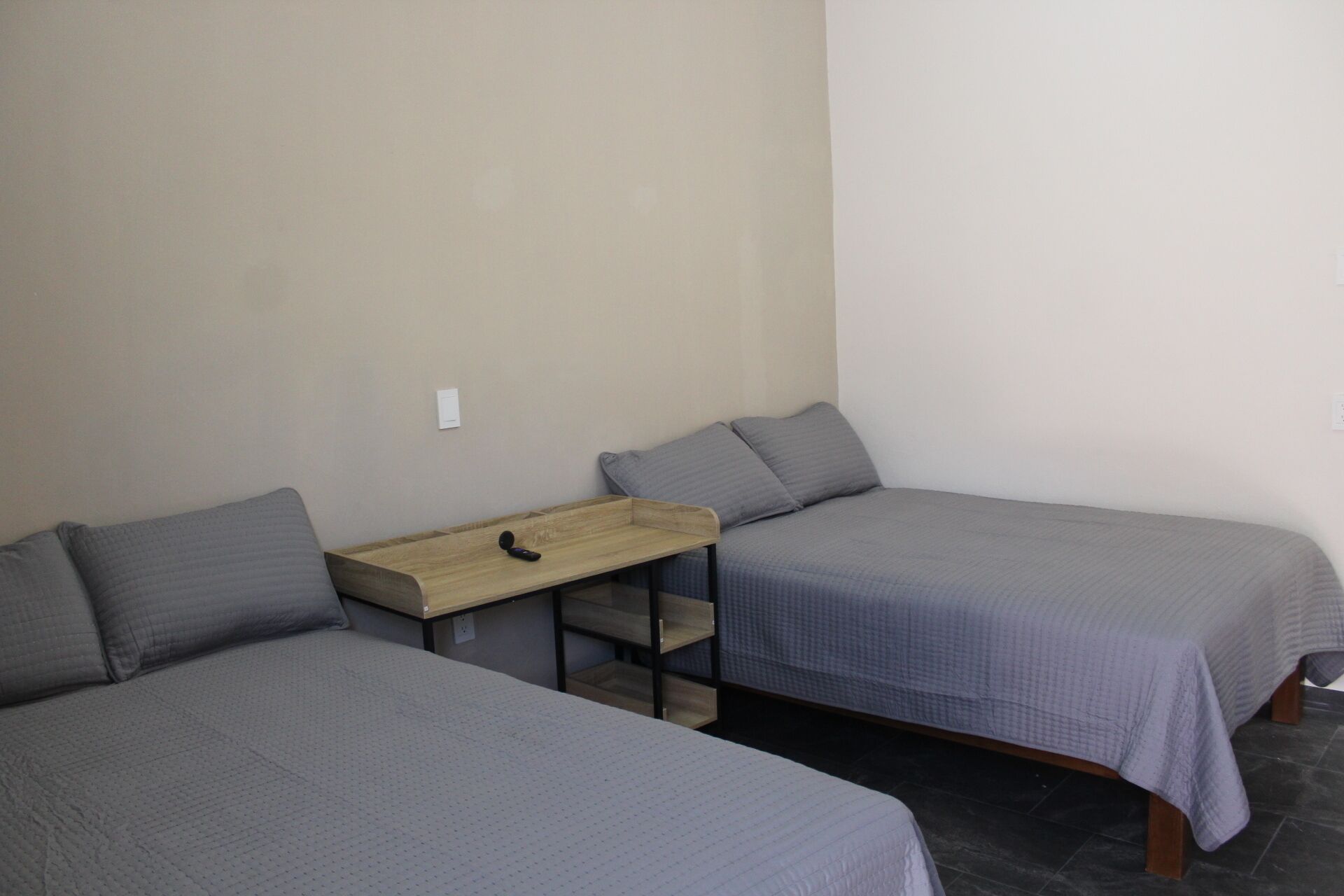 Une chambre avec deux lits, une petite table en bois et une chaise.