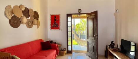 A spacious living room with a red sofa, a wooden TV stand, and a wall decorated with circular objects.