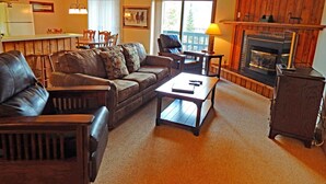 A cozy living room with a leather sofa, a wooden coffee table, and a fireplace. - Timber Run (Winter Park)