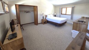 A bedroom with a bed, bedside table, lamp, and a desk with a computer. - Timber Run (Winter Park)