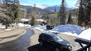 A black SUV parked on a snow-covered road with a mountain view in the background. - Timber Run (Winter Park)
