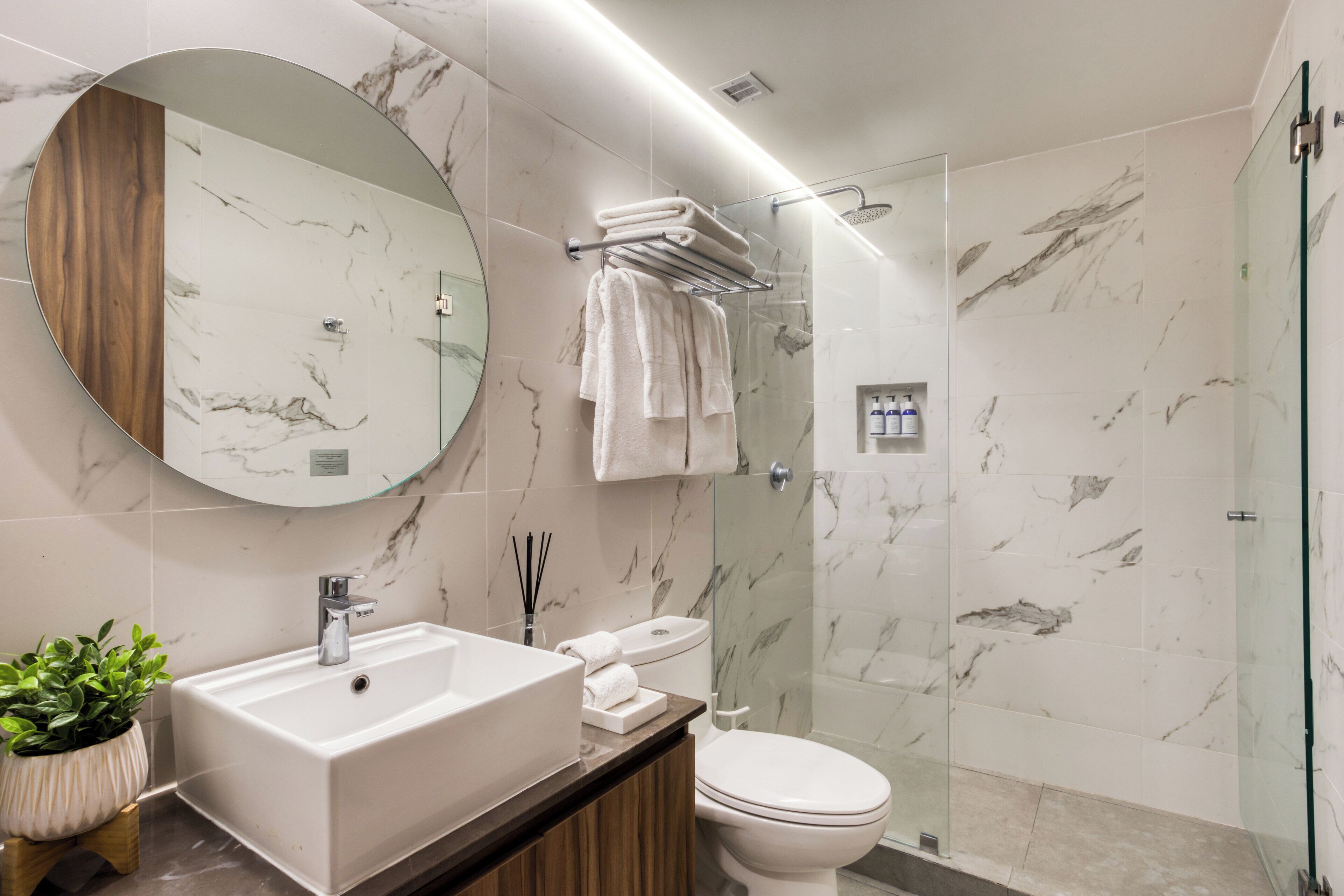 A modern bathroom with a marble sink, toilet, and shower.