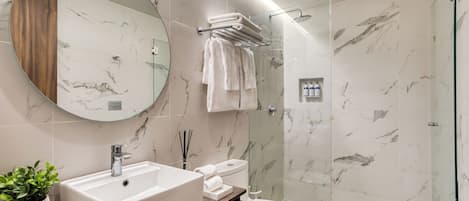 A modern bathroom with a marble sink, toilet, and shower.